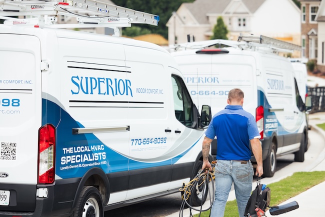 Technician carrying work gear next to a Superior work van
