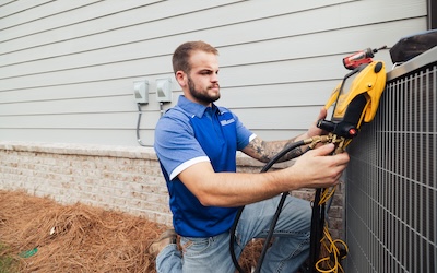 Service technician working on an air conditioner outside a home