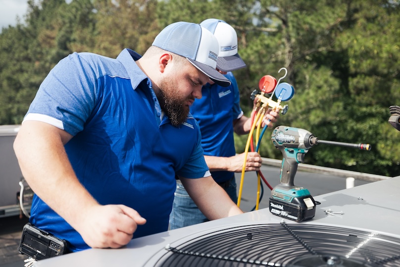 Technicians installing a commercial air conditioner