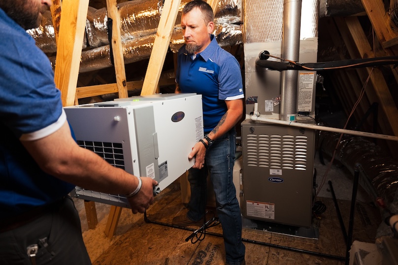 Two Superior Indoor Comfort technicians installing IAQ equipment