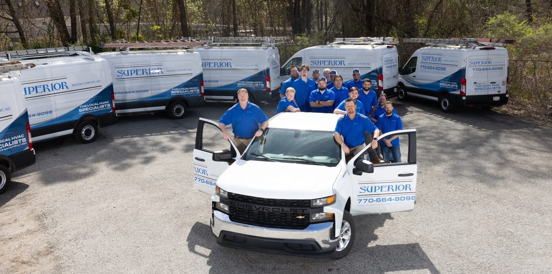 Superior Indoor Comfort crew standing in a truck in front of their fleet