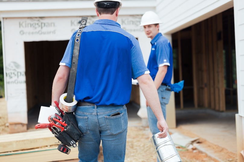 Men walking in to a new construction site with their tools and hard hats