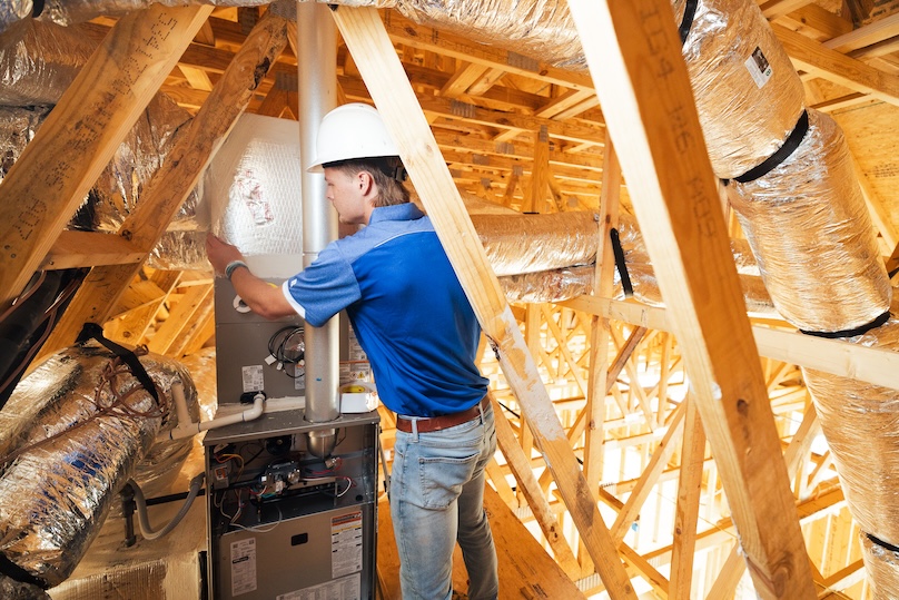 Technician installing a furnace in a new construction home